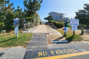 A private beach access area with a wooden walkway leading to a pool, marked with 'NO PARKING' and 'PRIVATE NO PARKING' signs. - Our Legacy - Dog Friendly Oceanside 4 BR Cottage with Community Pool access (Duck)
