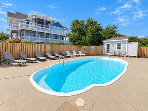 Una piscina con sillones de descanso y una cerca de madera.