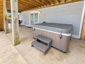 An outdoor hot tub area with a wooden deck, a bench, and a covered seating area. - A SHORE DELIGHT - ⛱️ Oceanside 5 BR home w/Private Pool, Hot Tub, and Pool Table ⛱️ (Corolla)