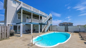 Une maison à deux étages avec une piscine, un espace salon extérieur et un patio couvert.