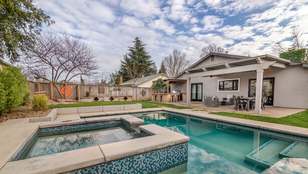 A backyard with a swimming pool, a patio with outdoor furniture, and a fenced area with trees. - Comfy House W/ Big Pool (Elk Grove)