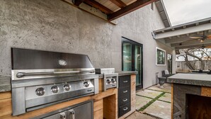 An outdoor kitchen with a stainless steel range, wooden cabinets, and a built-in refrigerator. - Comfy House W/ Big Pool (Elk Grove)