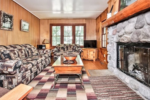 A cozy living room with a patterned sofa, a wooden coffee table, and a stone fireplace.