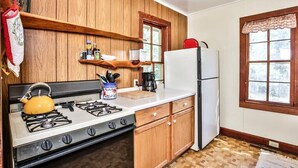 Una cucina con mobili in legno, piano cottura a gas, frigorifero e una finestra con vista.