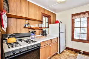 Eine Küche mit Holzschränken, einem Gasherd, einem Kühlschrank und einem Fenster mit Blick.