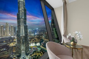 A modern interior with a large window offering a cityscape view, a comfortable seating area, and a decorative orchid plant.
