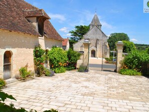 A courtyard with a stone pathway leading to a church with a cross on top. - Spacious Historic Presbytery, Sleeps 15, Garden, WiFi, Near Châteaux & La Roche-Posay (Bossay-sur-Claise)