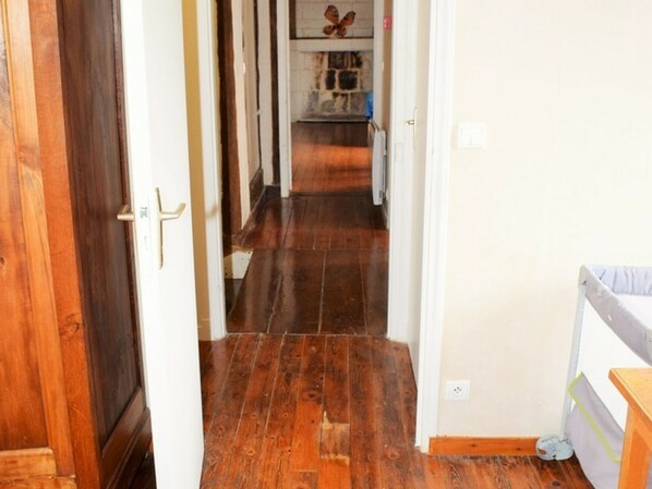 Un couloir étroit, doté d’un plancher en bois, mène à une cuisine.