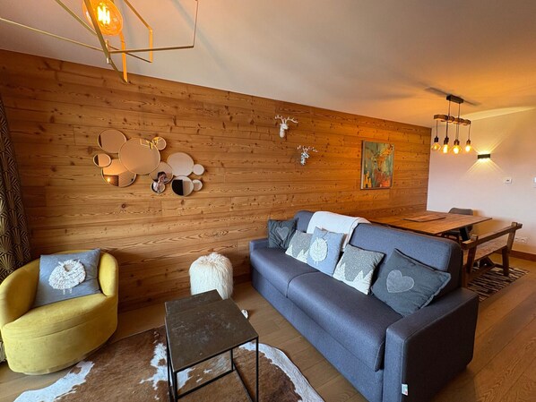 Una sala de estar moderna con pared de madera, un sofá, una mesita y un comedor.