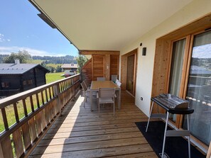 A wooden deck with a table and chairs, overlooking a scenic landscape.