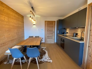 Uma cozinha moderna com mesa e cadeiras de madeira, tapete de couro e luminária pendente.