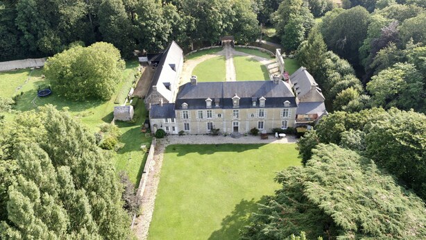 An aerial view of a large, historic estate with a symmetrical layout, including a central lawn, a formal garden, and a large building with multiple windows and a prominent entrance. - 17th century château in its original state, near Bayeux and the D-Day landing beaches (Vaux-sur-Seulles)