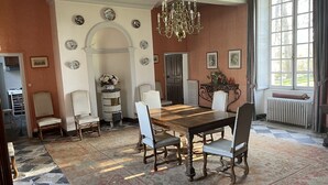 A dining room with a large wooden table, six chairs, a chandelier, and a patterned rug. - 17th century château in its original state, near Bayeux and the D-Day landing beaches (Vaux-sur-Seulles)