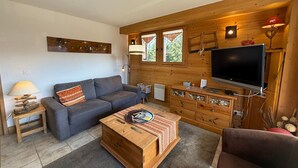 Un salon chaleureux avec un canapé gris, une table basse en bois et un téléviseur.