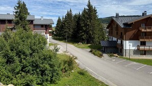 Un quartier résidentiel composé de deux immeubles à plusieurs étages, d’une route asphaltée et d’espaces verts environnants.