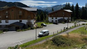 Un bâtiment en bois à deux étages, doté d’un balcon, d’un parking et surplombant un paysage montagneux.