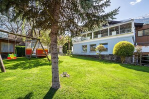 Una casa con un ampio giardino anteriore, un’altalena e un prato ben curato.