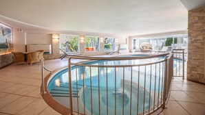 Uma área de piscina com design circular, cercada por espreguiçadeiras e um muro de pedra.