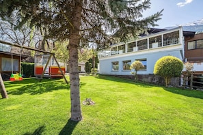 Il s’agit d’une propriété résidentielle dotée d’une pelouse bien entretenue, d’une balançoire et d’une maison moderne à deux étages avec de grandes fenêtres.