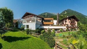 A hotel with multiple floors, outdoor seating, and a mountainous backdrop.
