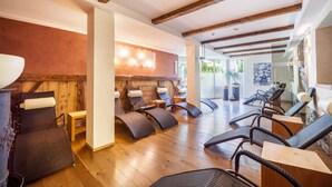 A spa area with wooden beams, reclining chairs, and a wall-mounted light fixture.
