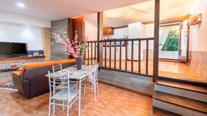 Un salon comprenant un canapé, une table à manger, des chaises, un téléviseur et un vase décoratif.