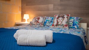 Un lit avec une couette bleue, des serviettes blanches et des oreillers à motifs.