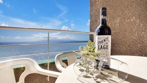 Una botella de vino Puente de Lago, una copa y una mesa con vistas al mar.