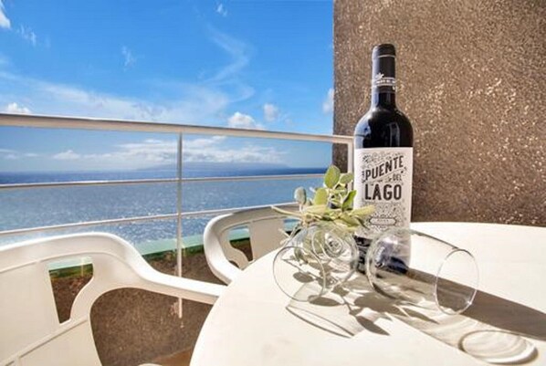A bottle of Puente de Lago wine, a glass, and a table with a view of the sea.