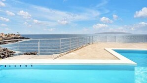 Una piscina con vista al océano y a la costa rocosa.