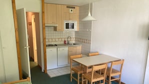 A compact kitchen with a dining area, featuring a dishwasher, a microwave, and a tiled backsplash.
