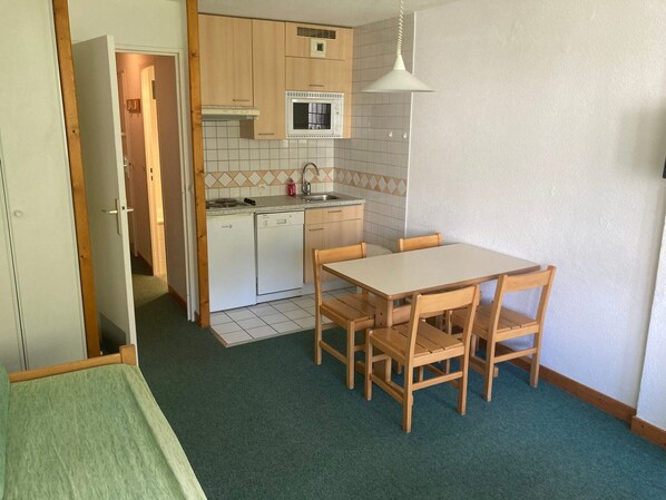 Kompakti keittiö, jossa on ruokailutila sekä astianpesukone, mikroaaltouuni ja laatoitettu välitila.
