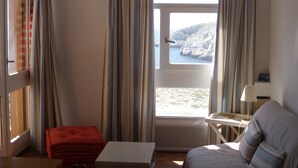 A room with a bed, a small table, a chair, and a window with curtains. - Ile du Frioul, 4-bed apartment at the foot of the calanques (Marseille)