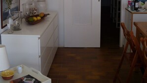 A small, well-lit room with a white door, a wooden dining table, a chair, a small white cabinet, and a tray with a bowl and a book. - Ile du Frioul, 4-bed apartment at the foot of the calanques (Marseille)