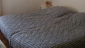 A bedroom with a checkered bedspread, a bedside table with a lamp, and a framed picture on the wall. - Ile du Frioul, 4-bed apartment at the foot of the calanques (Marseille)