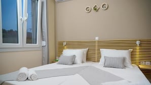 A hotel room with a bed, pillows, a bedside table, and a window. - Deatached apartment with shared pool in Tersanas Chania 2 minutes from the beach (chania)