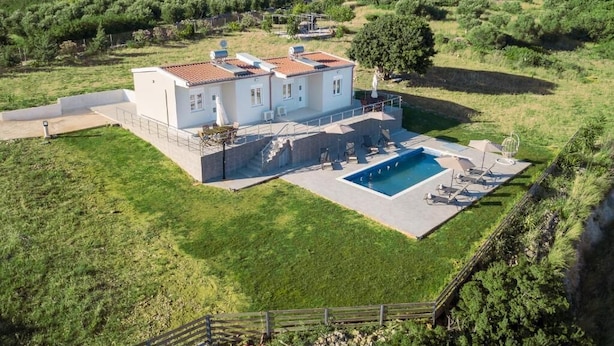 A two-story house with a swimming pool, surrounded by a well-maintained lawn and mountains in the background. - Deatached apartment with shared pool in Tersanas Chania 2 minutes from the beach (chania)