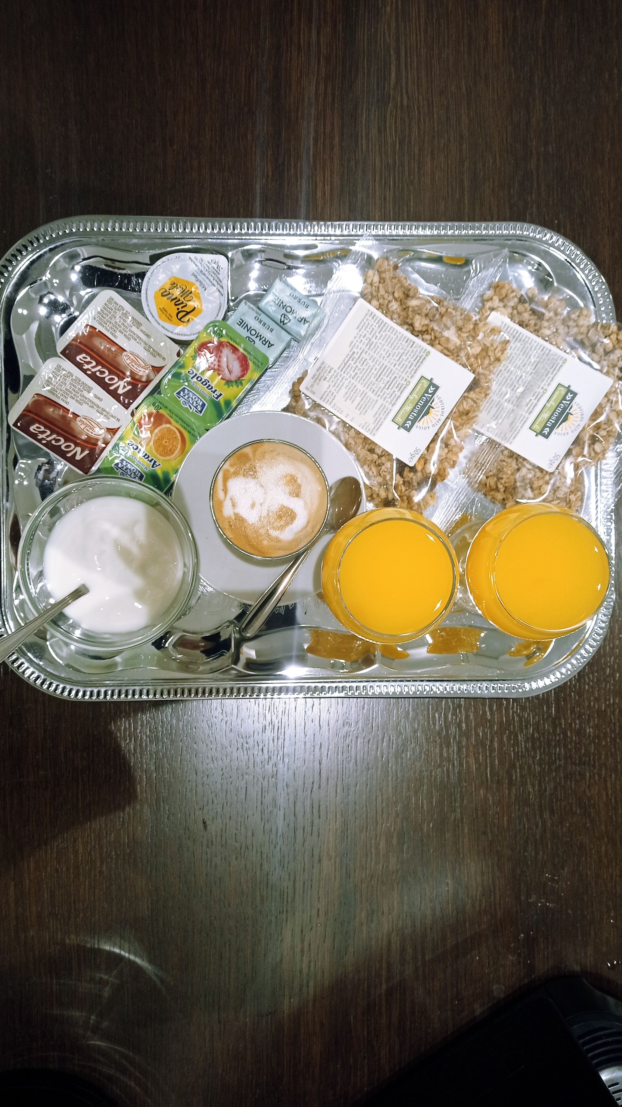 Un plateau de petit-déjeuner avec du yaourt, des céréales, un muffin et du jus d’orange.
