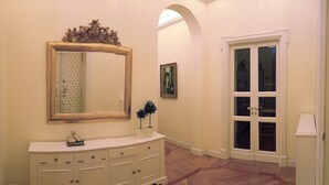 A hallway with a large mirror, a vanity with drawers, a painting, and a double door. - Roman Holidays Boutique (Rome)