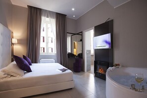 A modern hotel room with a bed, a fireplace, a TV, and a bathtub with a glass of wine. - Roman Holidays Boutique (Rome)