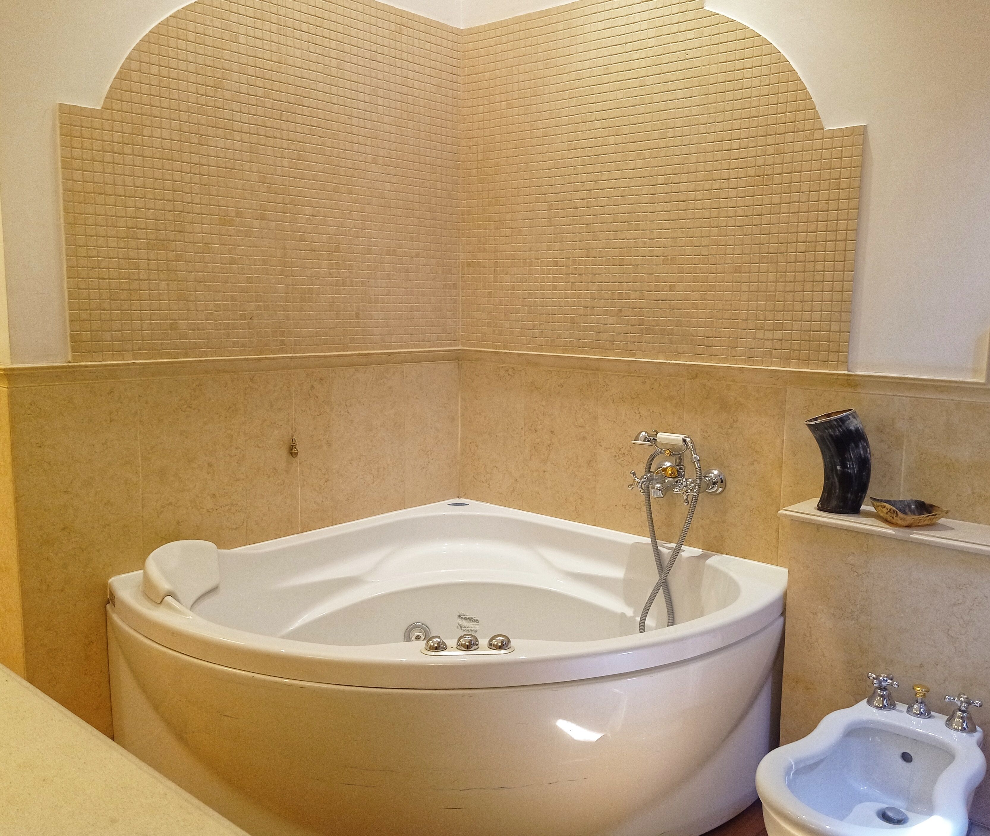 A bathroom with a large freestanding bathtub, a bidet, and a small shelf with decorative items.