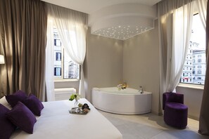 A modern hotel room with a large bed, a round bathtub, and a small purple chair. - Roman Holidays Boutique (Rome)