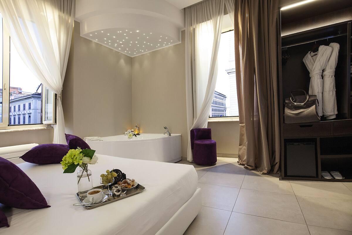 A modern hotel room with a large bed, a bathroom, and a walk-in closet.