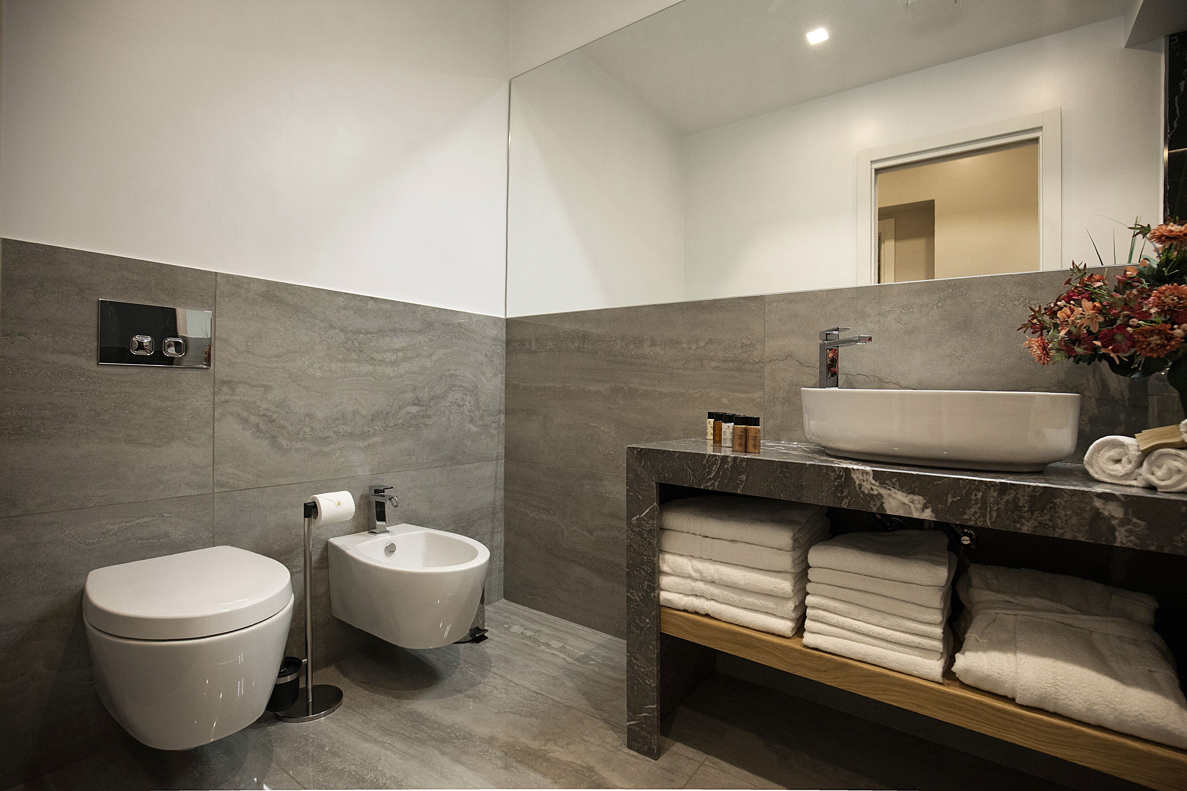 Une salle de bain moderne équipée de toilettes, d’un bidet et d’un meuble-lavabo avec un évier et des serviettes.