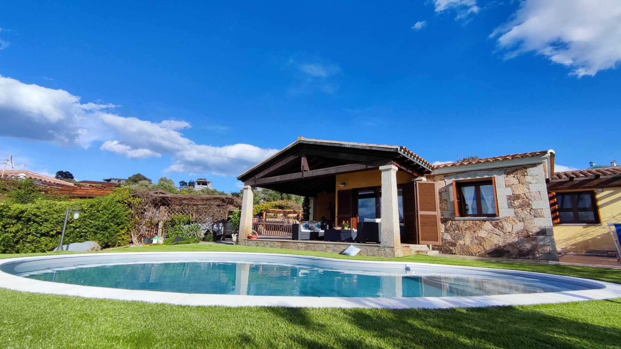 Uma casa com piscina, varanda coberta e fachada de pedra.