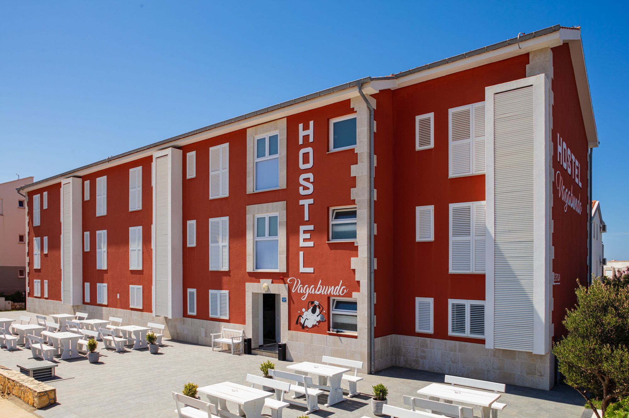 Un edificio de hostal rojo con contraventanas blancas y un letrero que dice "Hostel Vagabundo".