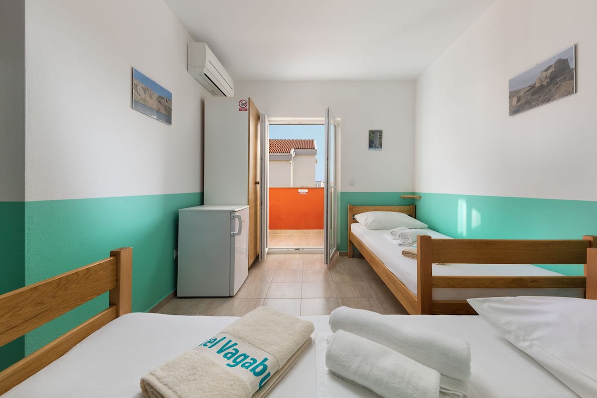 A room with two beds, a small fridge, and a door leading to an outdoor area.