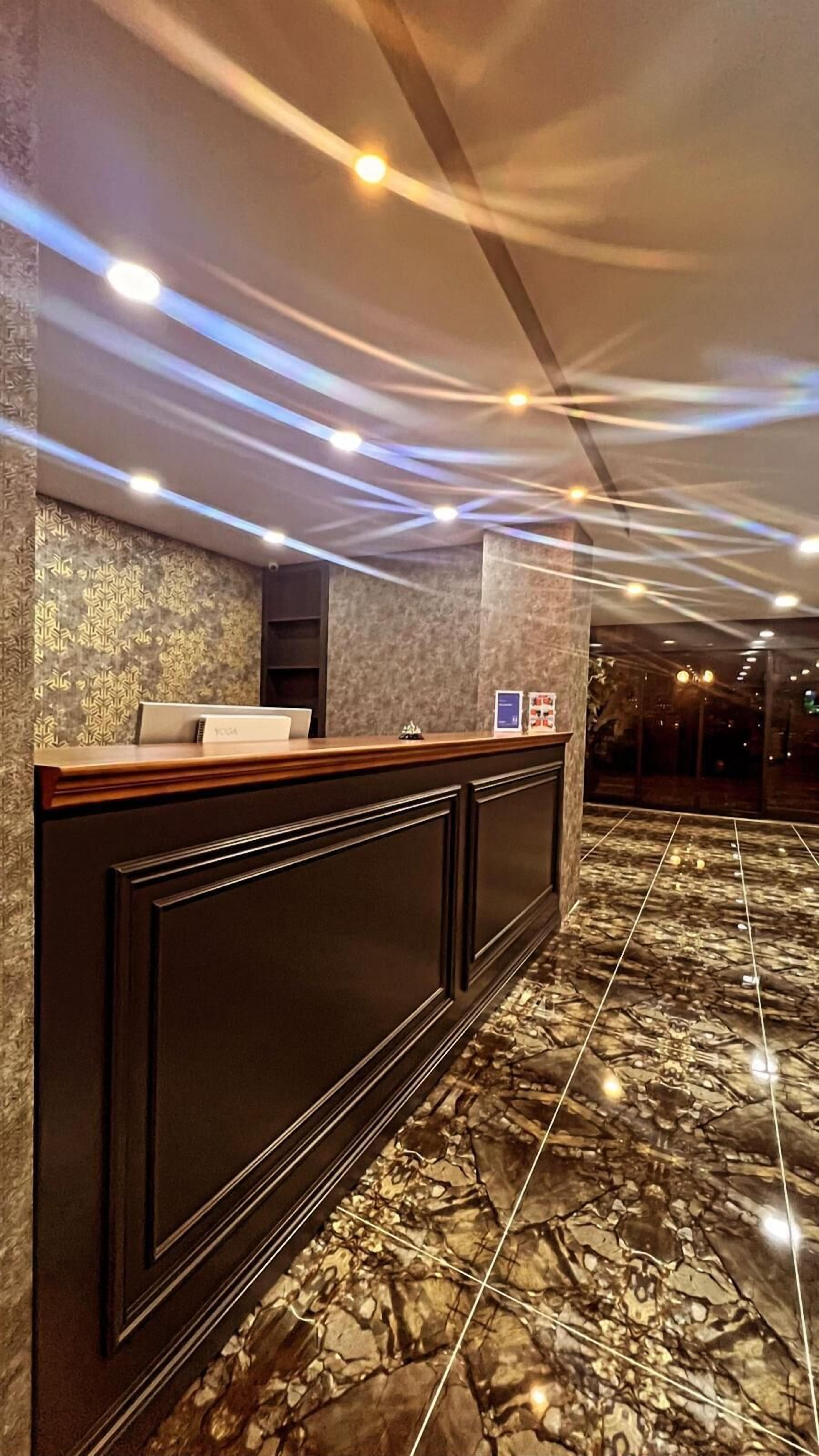Un área de recepción con suelo de mármol, mostrador de recepción y pared con diseño.