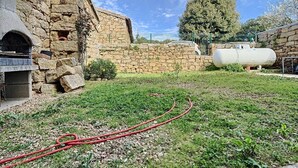 A stone building with a brick oven, a grassy area, and a large white tank.