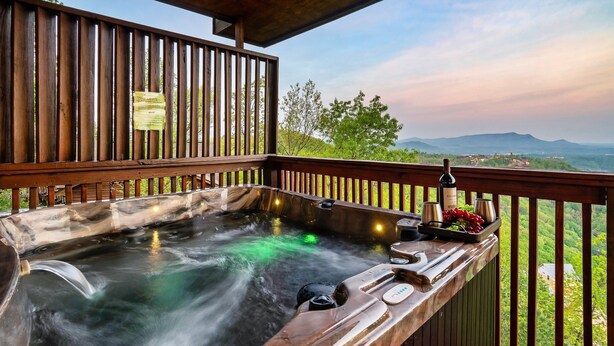 A hot tub with a wooden deck and a view of the landscape. - TopOfTheMountain, Fully Paved Roads, PoolTable, HotTub, VideoGames,EV Charger (Sevierville)